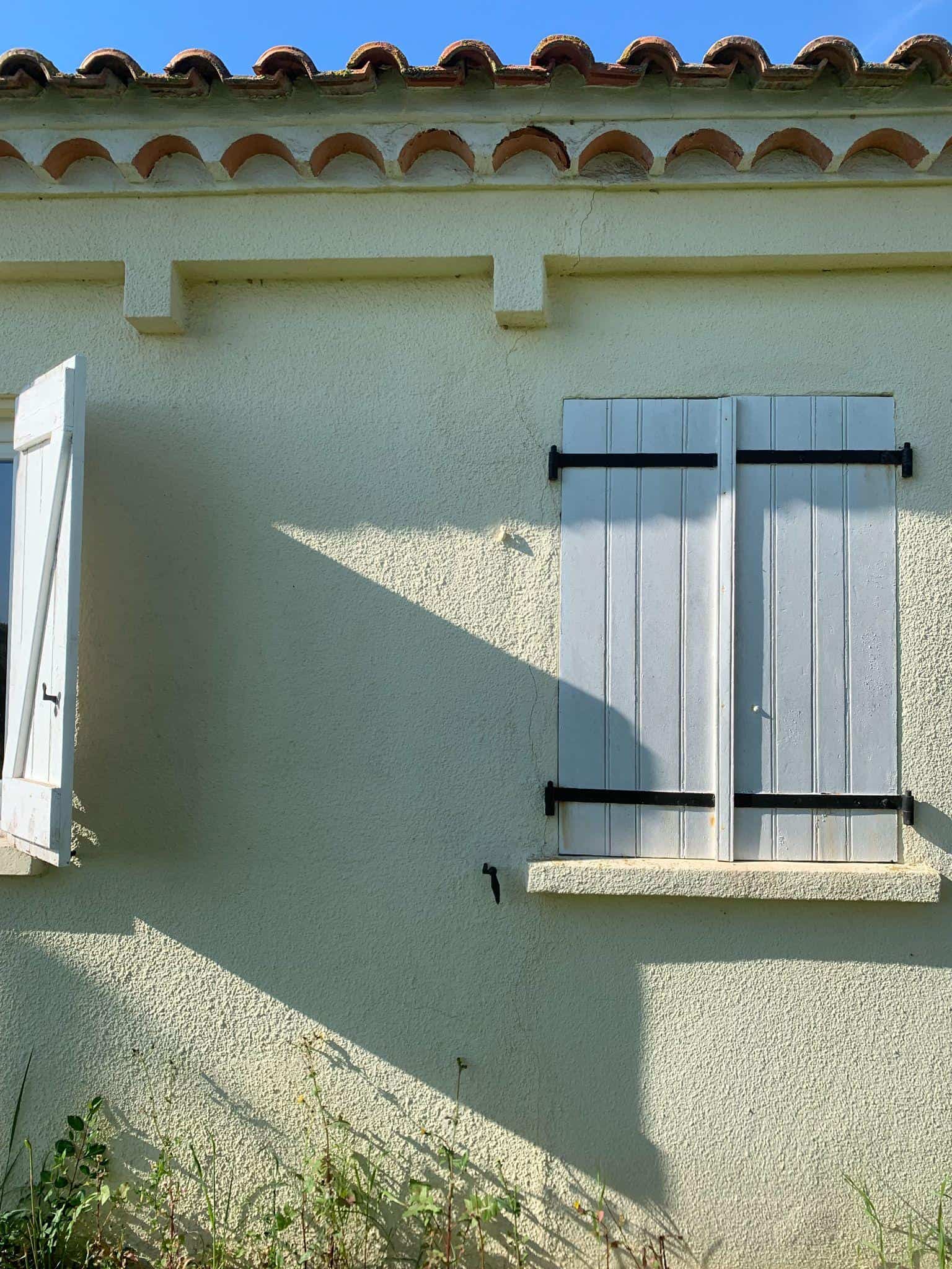 fissure verticale façade enduit au dessus fenetre volets bois maison ancienne
