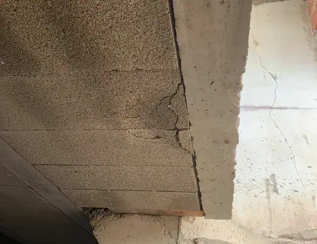 Épaufrure béton sur un hourdis de plancher : éclats en sous-face et fissures suivant la ligne des armatures.