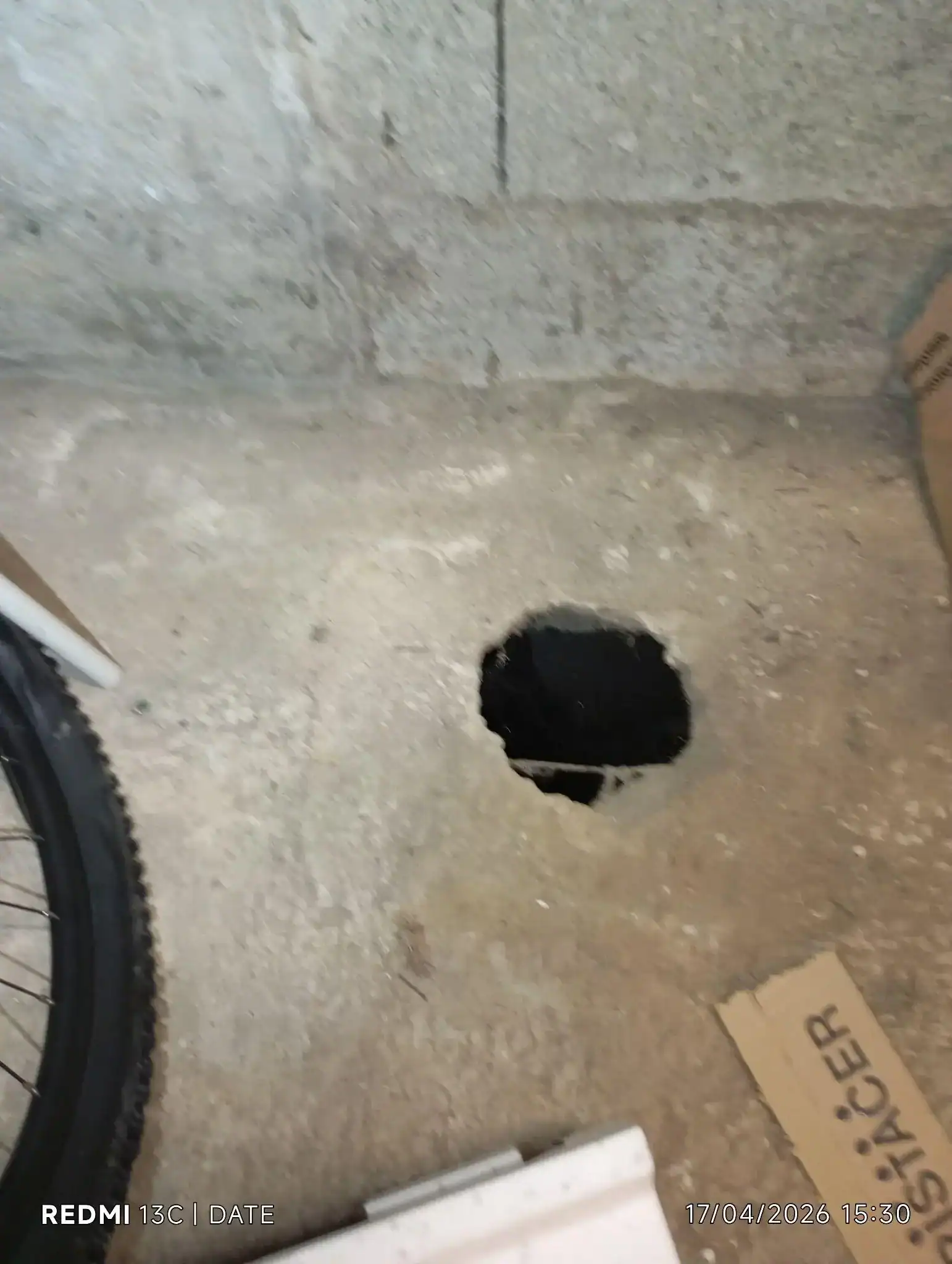 Ouverture dans la dalle béton donnant sur un vide sanitaire humide, facteur aggravant sous une maison effondrée ou fissurée.