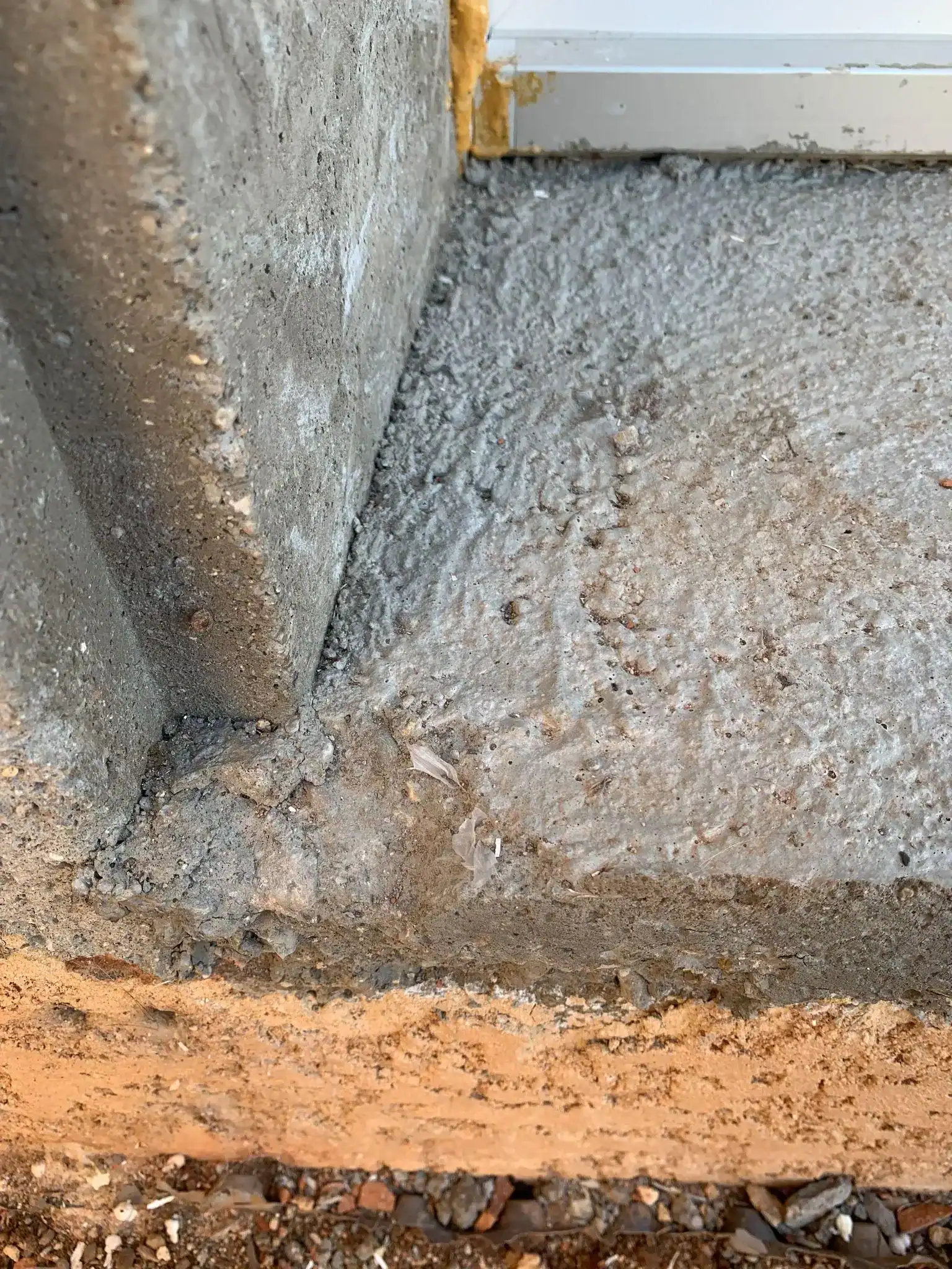 Finition inachevée en béton sur le tableau d'une porte-fenêtre, réserve à consigner avant un recours pour fenêtre mal posée.