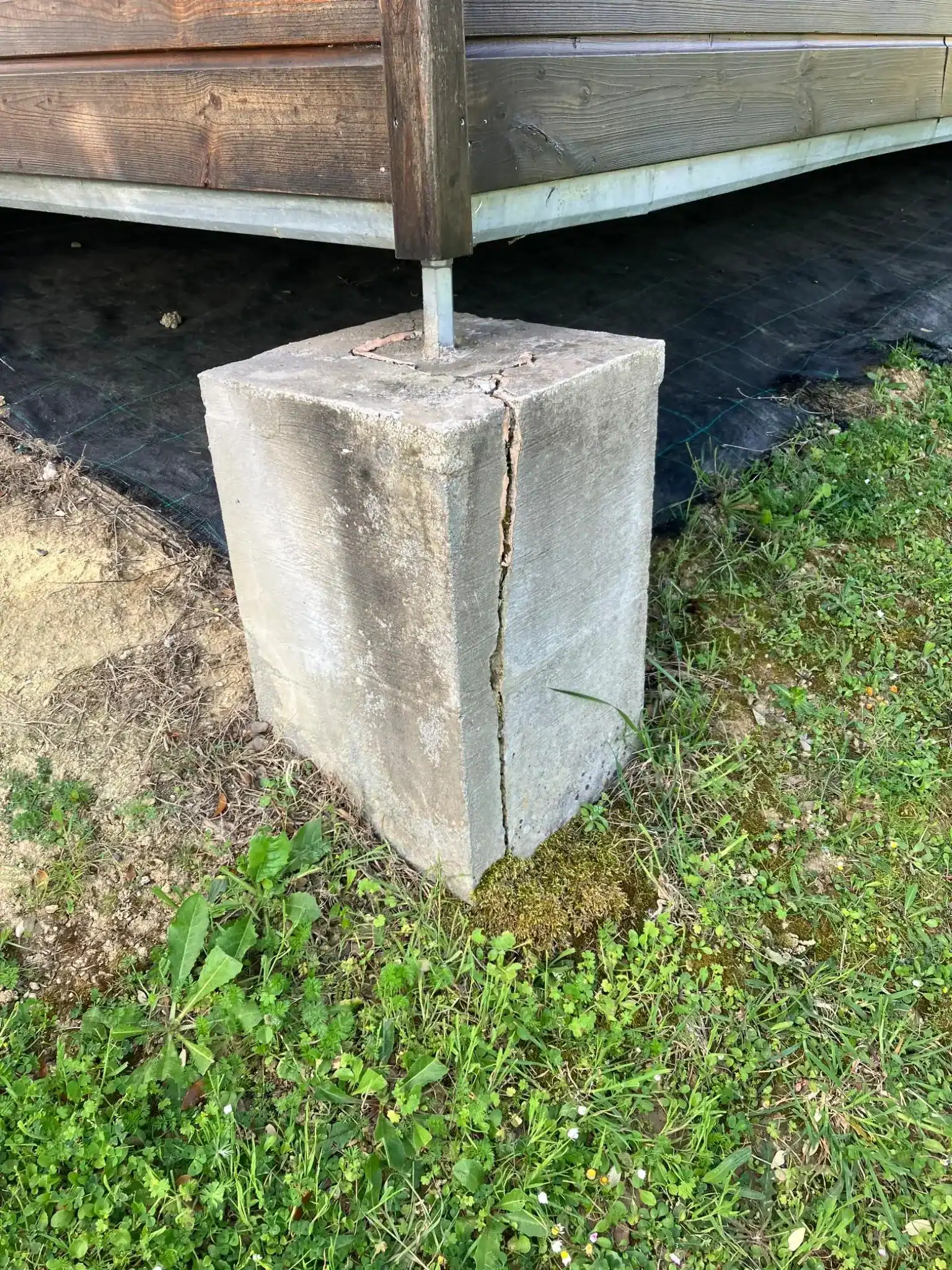 Bloc de fondation en béton fissuré sous un poteau, situation où une fondation sur pieux peut s'imposer après étude de sol.