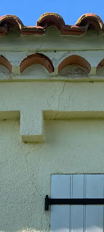Fissure verticale sur façade sous une génoise, point d'infiltration possible à écarter avant tout diagnostic de condensation.
