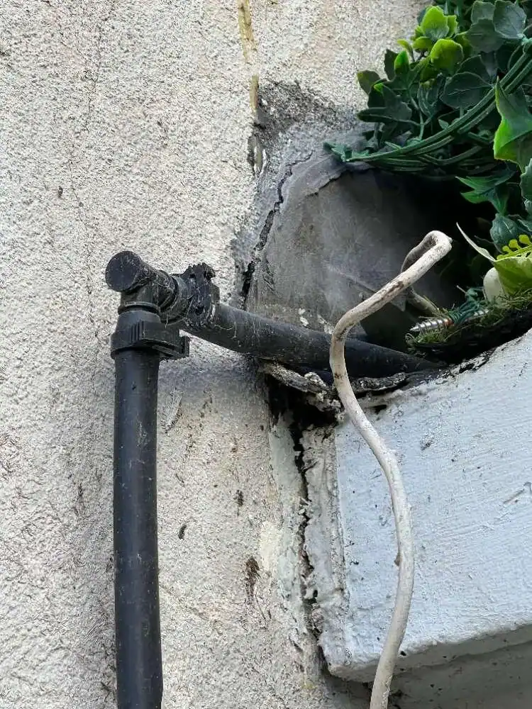 Fissure infiltrante au passage d'une canalisation sur un mur extérieur, source d'humidité et de moisissures en chambre.