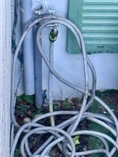 Descente d'eau pluviale déversant au pied d'un mur, source d'humidité qui abaisse la température de paroi vers le point de rosée.