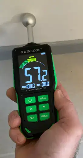 Humidimètre professionnel appliqué sur un mur intérieur pour quantifier l'humidité lors d'une expertise d'assuré.