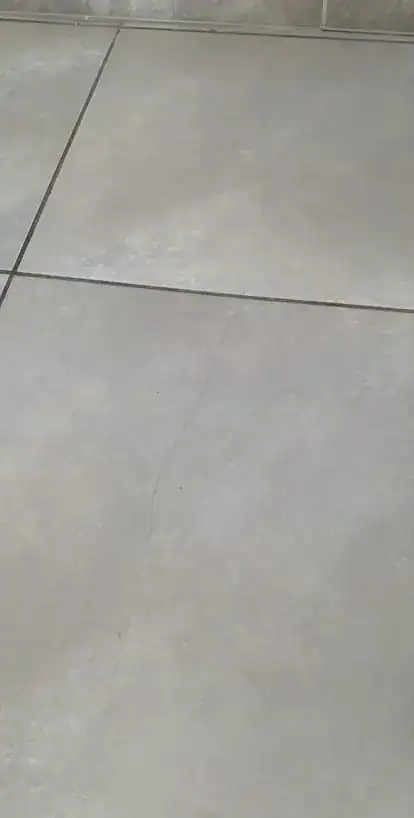Fissure linéaire traversant le carrelage d'un sol intérieur, désordre examiné lors d'une expertise après sinistre.
